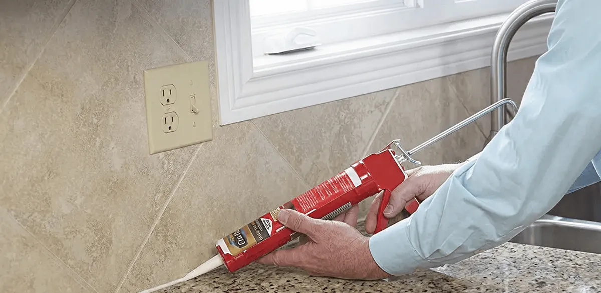 Handyman applying caulk along a kitchen backsplash and countertop seam in Cambridge, MA