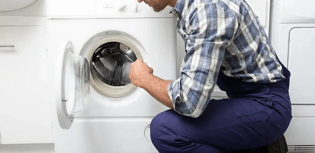 Handyman inspecting a dryer drum and internal parts for repair in Cambridge, MA