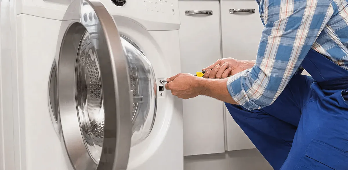 Handyman repairing a clothes dryer and checking electrical connections in Cambridge, MA