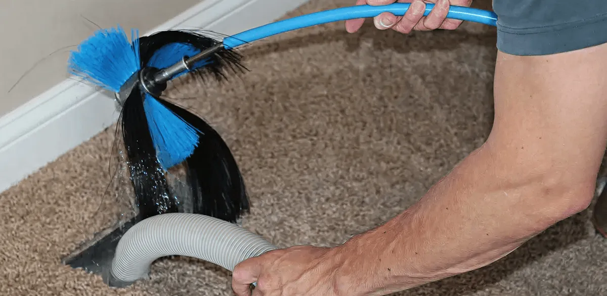 Dryer vent cleaning technician brushing lint from a vent line in Cambridge, MA