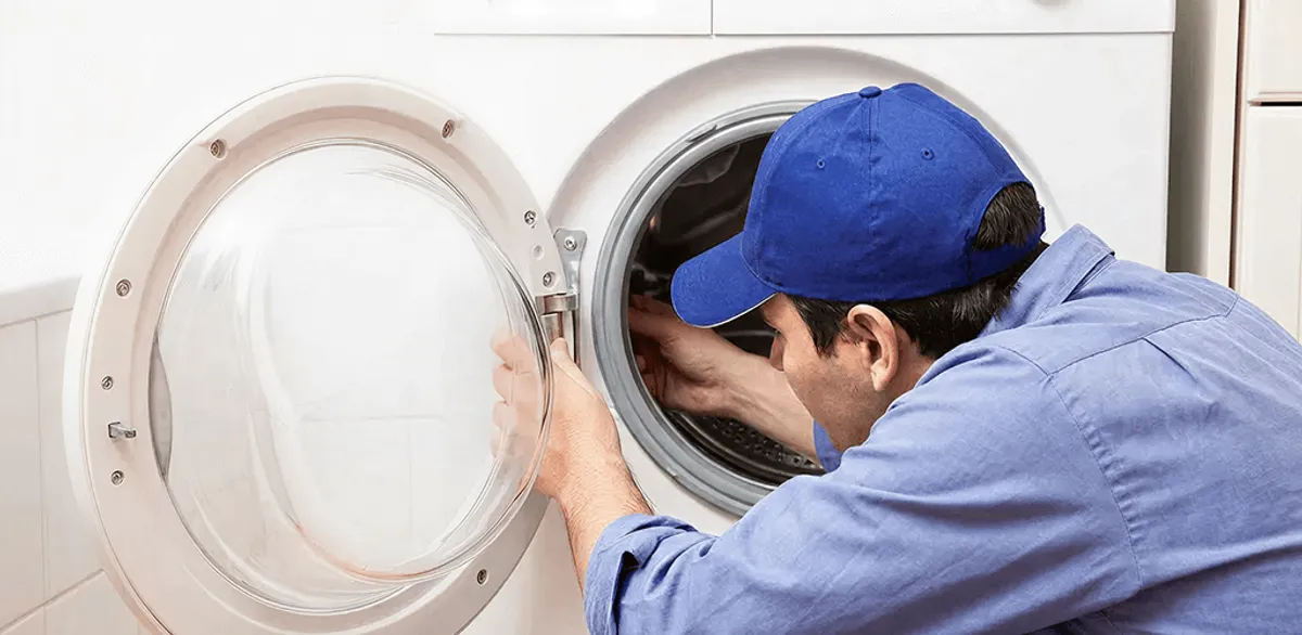 Washing machine repair handyman inspecting a front-load washer drum in Cambridge, MA