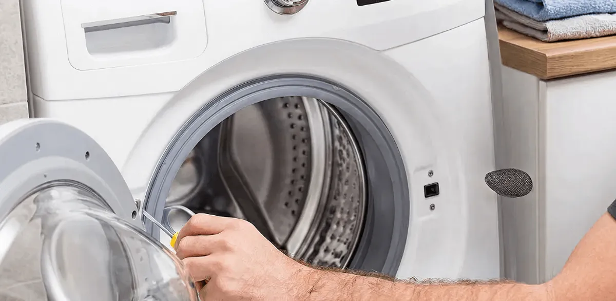 Handyman repairing a front-load washing machine and inspecting the drum in Cambridge, MA